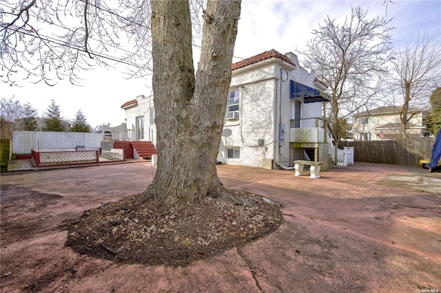 view of home's exterior with a tile roof, fence, and stucco siding