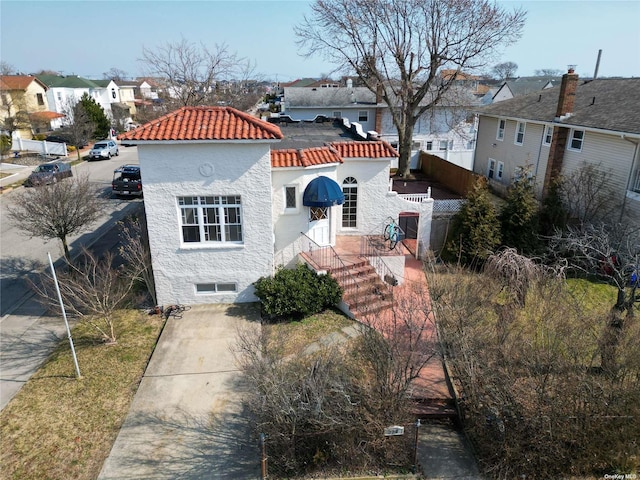 view of front of home featuring a tile roof, a residential view, fence, and stucco siding