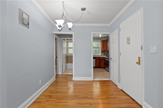 unfurnished dining area with light wood-style flooring, baseboards, a chandelier, and ornamental molding