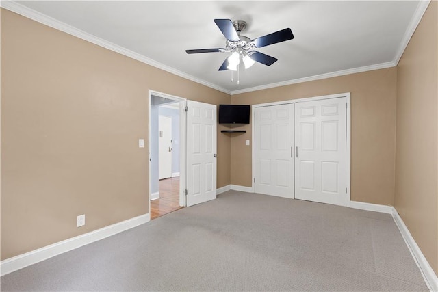 unfurnished bedroom with ornamental molding, a ceiling fan, a closet, carpet flooring, and baseboards