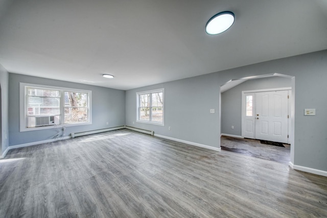 unfurnished living room featuring cooling unit, wood finished floors, baseboards, arched walkways, and a baseboard heating unit