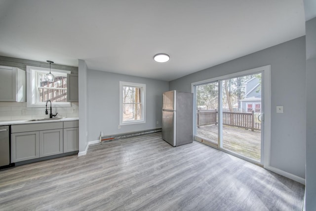 interior space featuring light wood finished floors, a healthy amount of sunlight, baseboards, and a sink