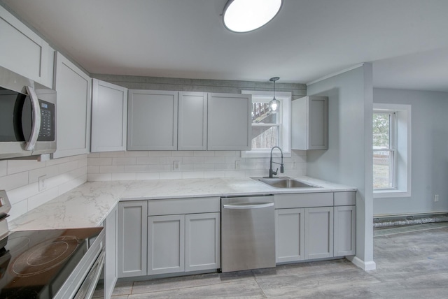 kitchen with tasteful backsplash, gray cabinets, appliances with stainless steel finishes, plenty of natural light, and a sink