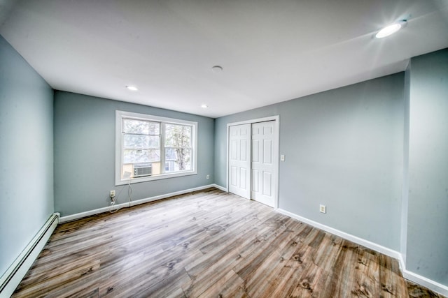 spare room with baseboards, recessed lighting, cooling unit, wood finished floors, and a baseboard radiator