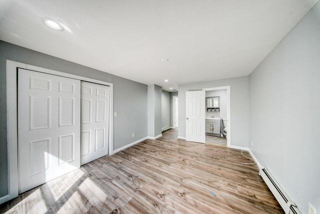 unfurnished bedroom featuring recessed lighting, a closet, light wood-style floors, a baseboard radiator, and baseboards