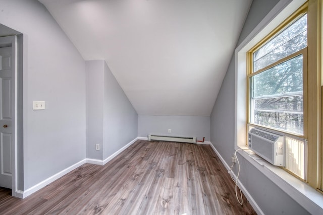 additional living space with baseboards, baseboard heating, wood finished floors, and vaulted ceiling