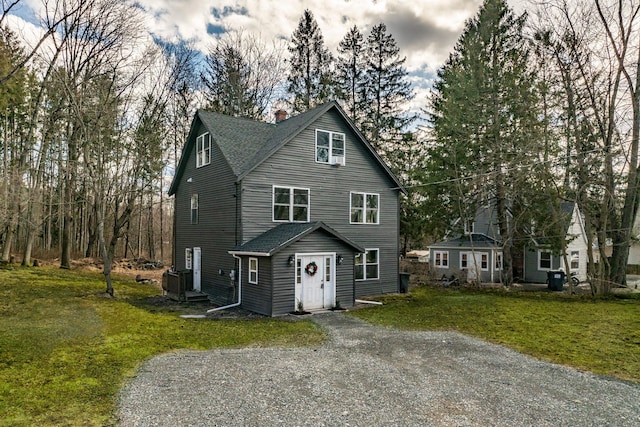 view of front of property with driveway, a chimney, a front lawn, and a shingled roof