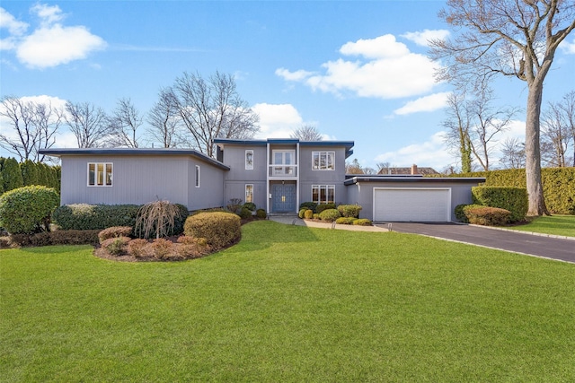 view of front of house featuring aphalt driveway, an attached garage, and a front lawn