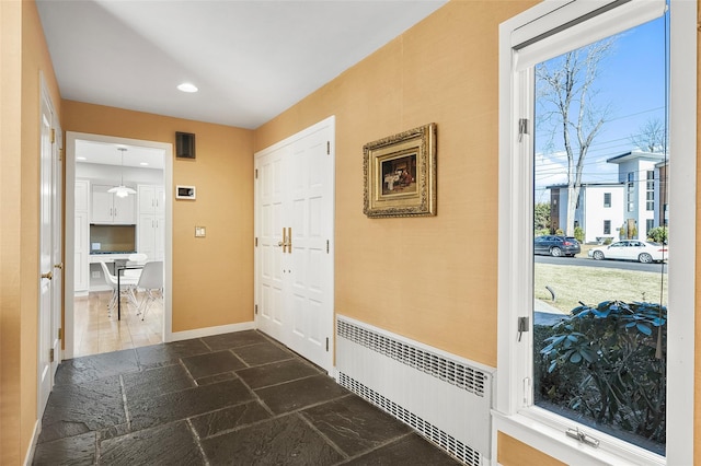 entryway featuring stone tile flooring, recessed lighting, radiator heating unit, and baseboards