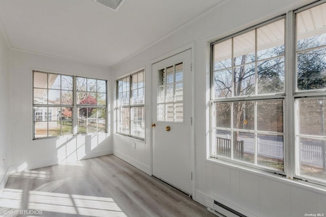 doorway to outside with a baseboard heating unit, visible vents, wood finished floors, and crown molding