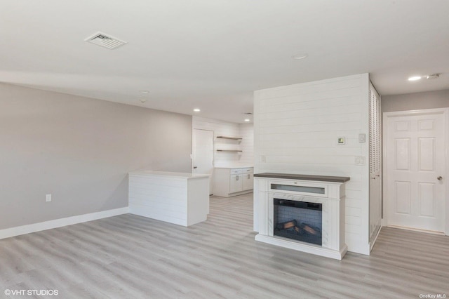 unfurnished living room with baseboards, visible vents, light wood-style flooring, a fireplace, and recessed lighting