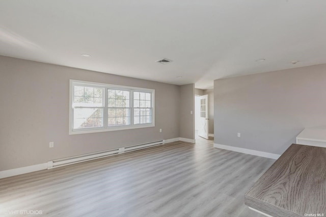 spare room featuring light wood finished floors, baseboards, visible vents, and baseboard heating