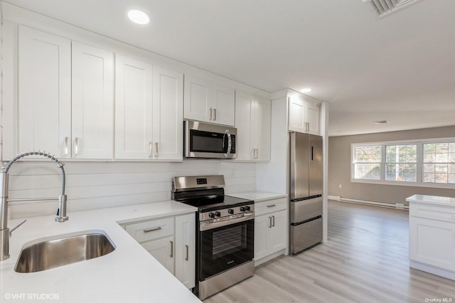 kitchen with visible vents, a sink, stainless steel appliances, light countertops, and baseboard heating