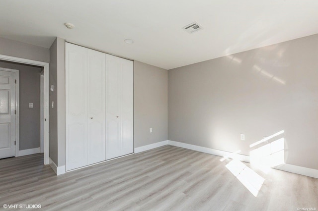 unfurnished bedroom featuring light wood-type flooring, baseboards, a closet, and visible vents