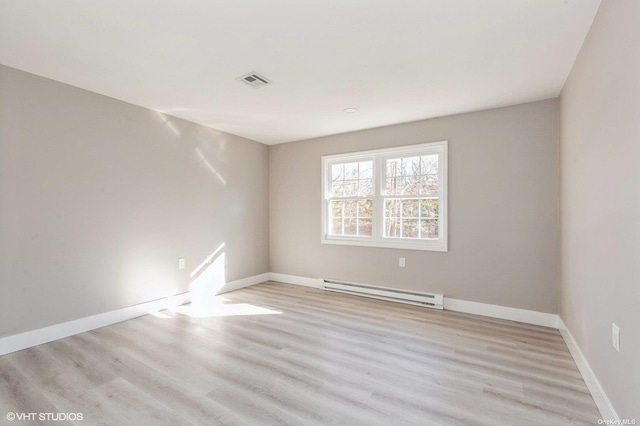 unfurnished room featuring a baseboard heating unit, baseboards, visible vents, and light wood finished floors