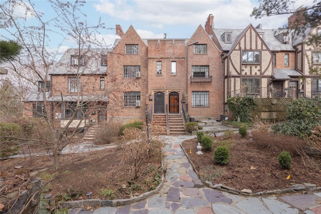 english style home with brick siding and a chimney