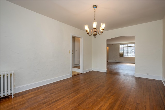 spare room featuring hardwood / wood-style flooring, radiator heating unit, and baseboards