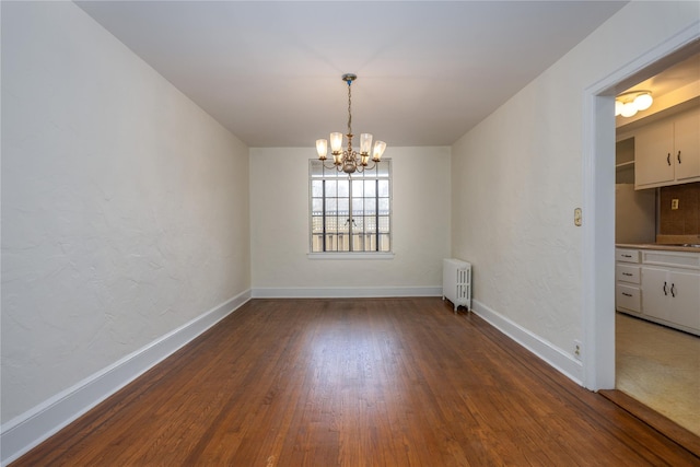 unfurnished dining area with a chandelier, radiator heating unit, baseboards, and wood finished floors