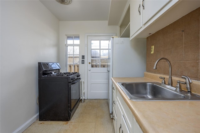 kitchen featuring decorative backsplash, white cabinetry, black range with gas stovetop, and a sink