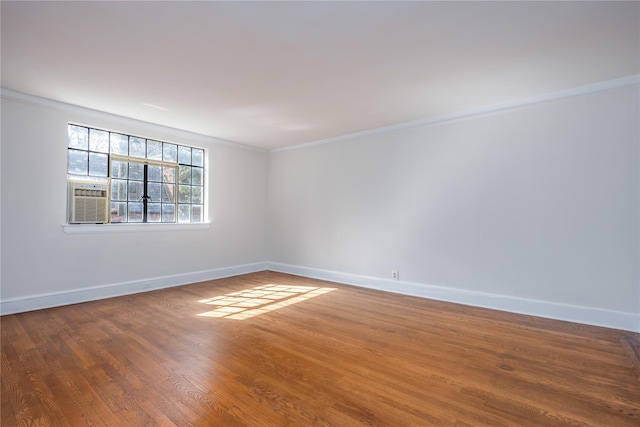 empty room with cooling unit, wood finished floors, baseboards, and ornamental molding