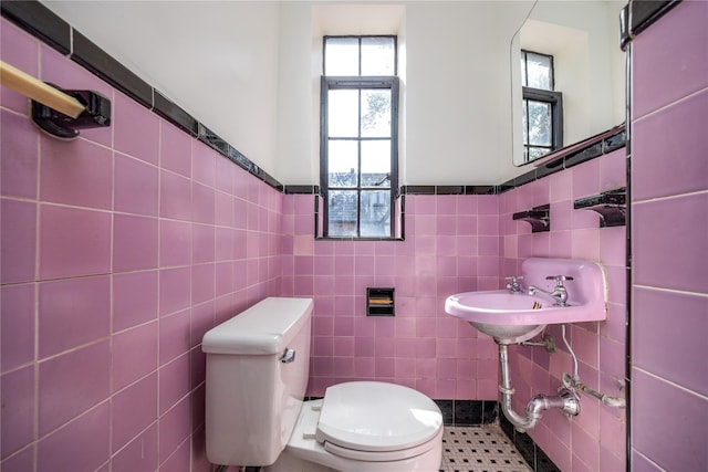 bathroom with tile walls, toilet, and a wainscoted wall