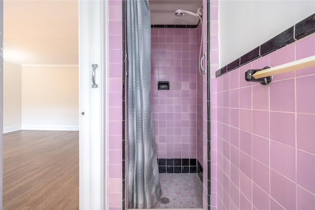 full bath with baseboards, wood finished floors, a shower stall, and ornamental molding