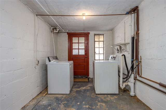 washroom with laundry area, concrete block wall, and washing machine and clothes dryer