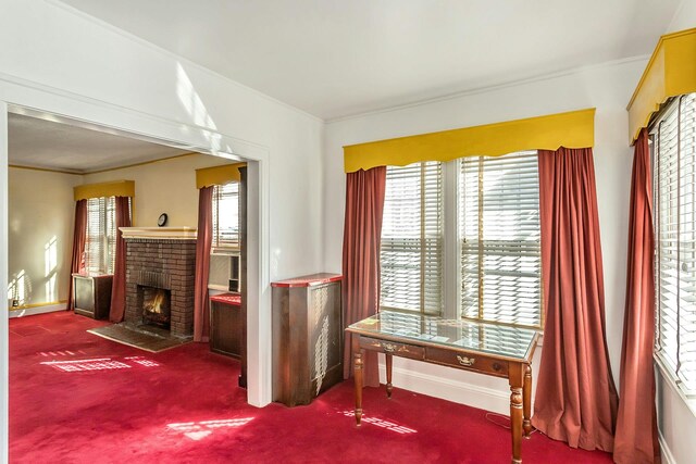 interior space featuring a brick fireplace, baseboards, crown molding, and carpet