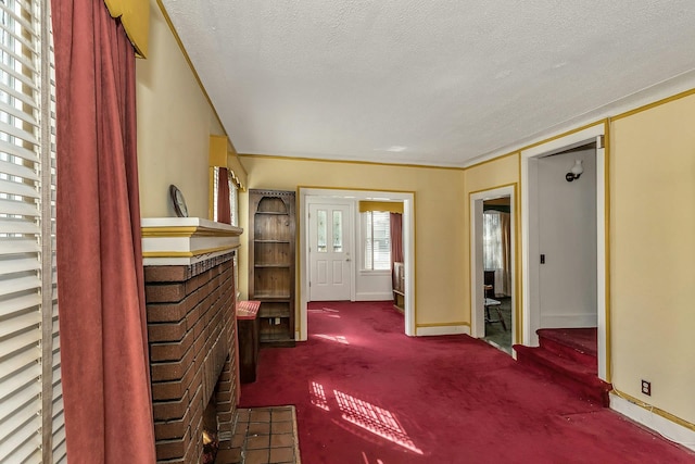 carpeted foyer featuring a textured ceiling and baseboards