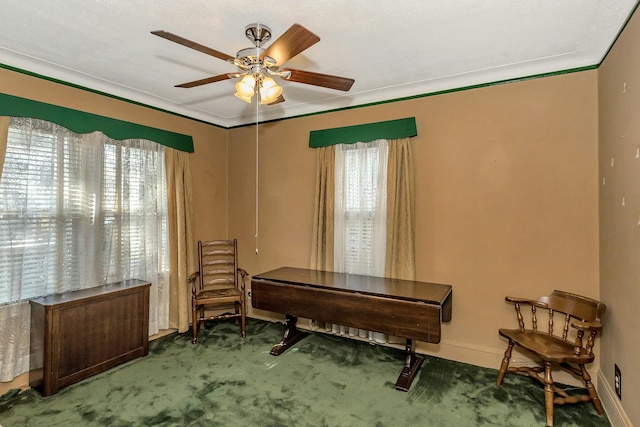 sitting room with baseboards, carpet, a ceiling fan, and crown molding