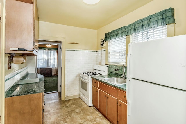 kitchen featuring plenty of natural light, white appliances, tile walls, and a sink