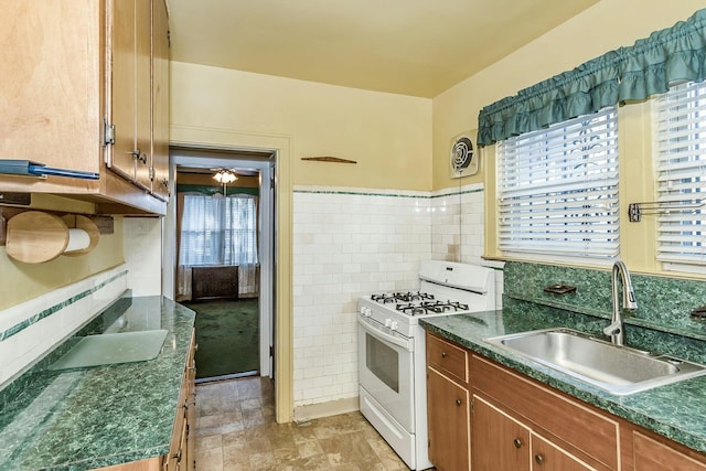 kitchen featuring dark countertops, visible vents, white range with gas stovetop, a sink, and tile walls