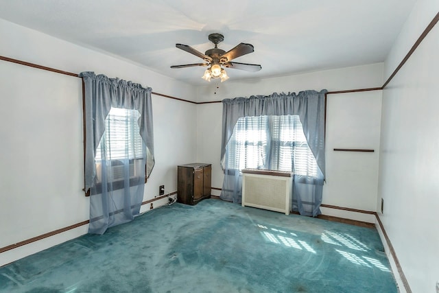 empty room with radiator, a ceiling fan, baseboards, and carpet floors