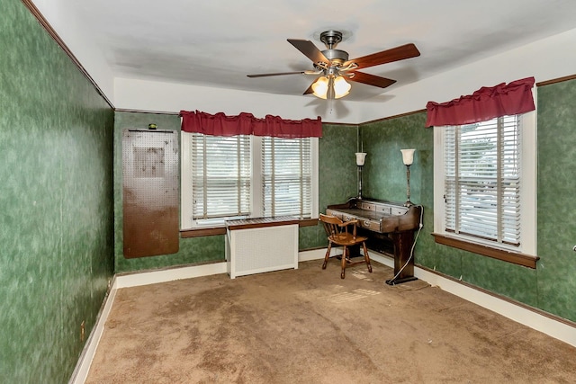 carpeted home office with radiator, baseboards, and a ceiling fan