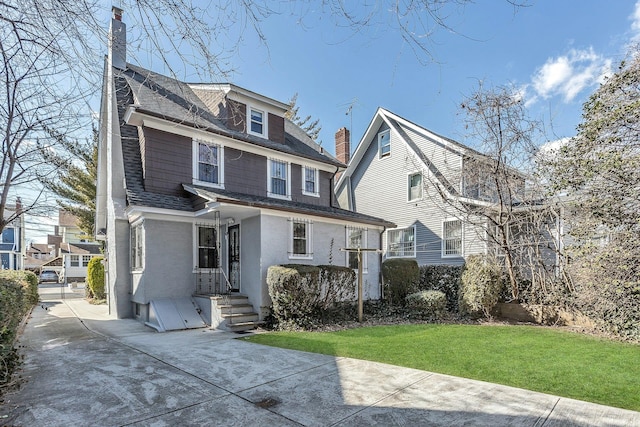 view of front of home with a front lawn, a chimney, and a shingled roof