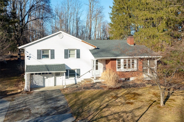 tri-level home with an attached garage, driveway, a chimney, and roof with shingles