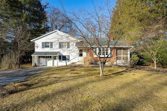 split level home with brick siding, a chimney, aphalt driveway, and a front yard