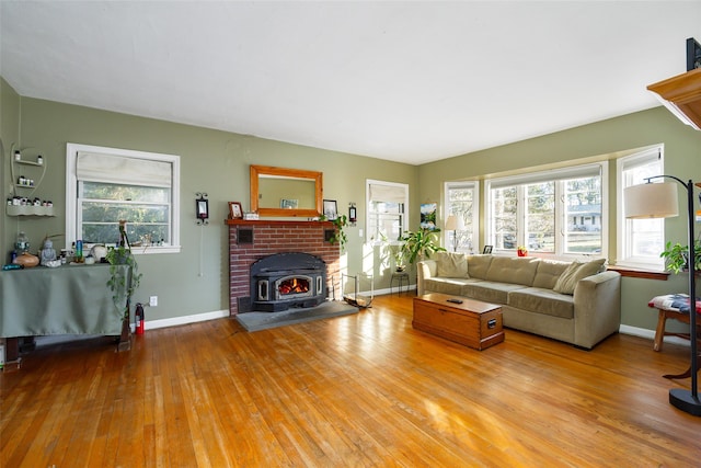 living room with a wealth of natural light, baseboards, a wood stove, and hardwood / wood-style flooring