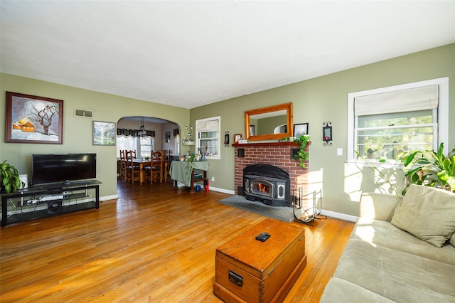 living area with baseboards, visible vents, a wood stove, arched walkways, and hardwood / wood-style flooring