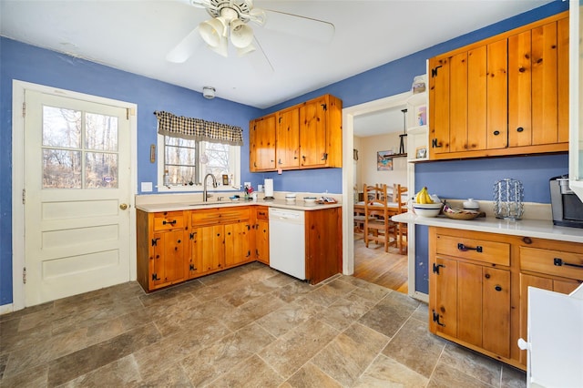 kitchen with a ceiling fan, a sink, light countertops, dishwasher, and brown cabinets