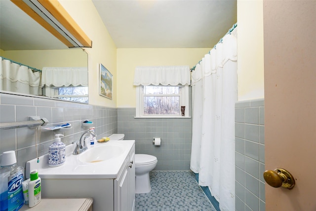 bathroom with vanity, a shower with curtain, a wainscoted wall, tile walls, and toilet