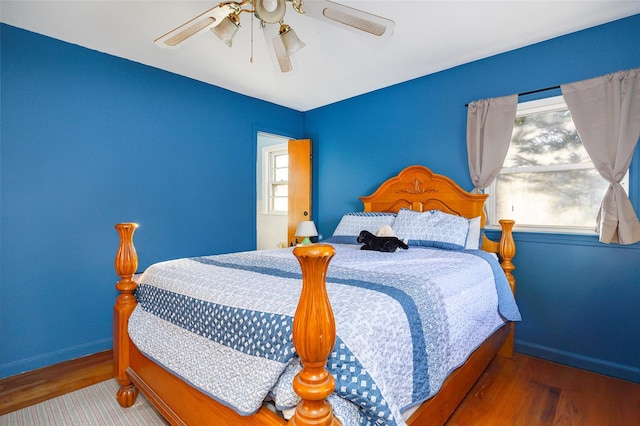 bedroom with baseboards, multiple windows, wood finished floors, and a ceiling fan