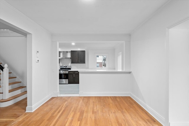 kitchen featuring stainless steel range with gas cooktop, light countertops, backsplash, light wood-style floors, and ornamental molding