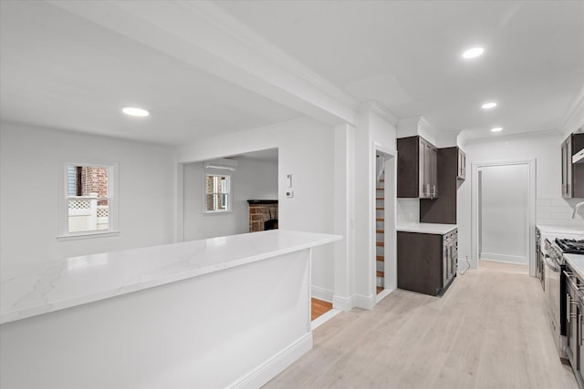 kitchen featuring stainless steel gas stove, dark brown cabinets, light wood-style floors, backsplash, and recessed lighting