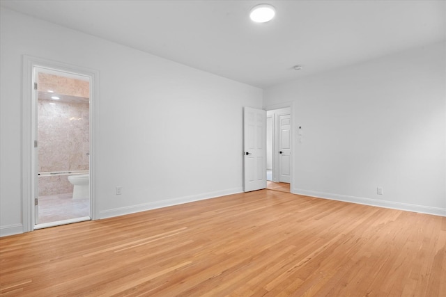 spare room with baseboards and light wood-style floors