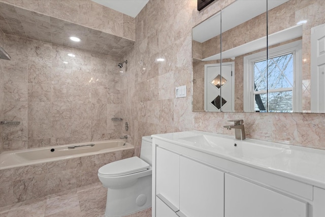 bathroom featuring tiled shower / bath combo, tile walls, toilet, and vanity