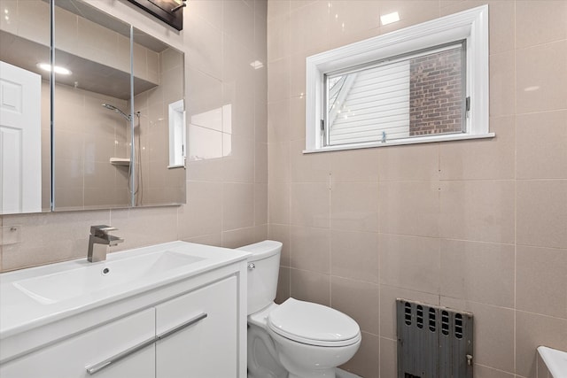 bathroom with toilet, radiator heating unit, tile walls, and vanity