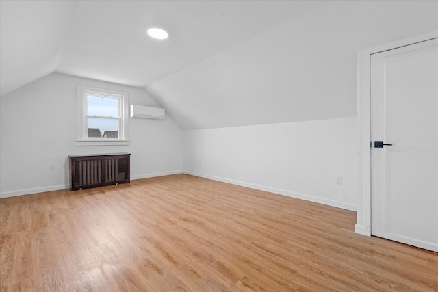 additional living space featuring lofted ceiling, radiator, light wood-style flooring, an AC wall unit, and baseboards