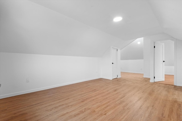 bonus room with lofted ceiling, light wood-style flooring, and baseboards