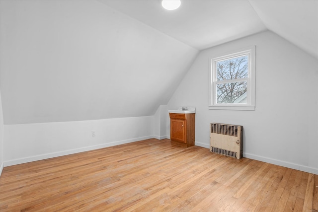 bonus room featuring light wood-type flooring, baseboards, lofted ceiling, and radiator heating unit